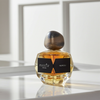 Perfume bottle labeled 'mood'or' on a reflective surface with a neutral background